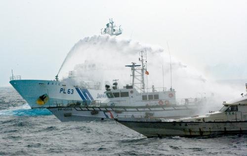 臺灣“海巡署”的巡邏船（中）在掩護保釣船“全家?！碧枺ㄓ遥┒惚苋毡竞Ｉ媳０矎d巡視船的水炮攻擊。